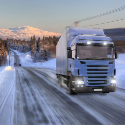 Blue truck driving on road in a winter landscape